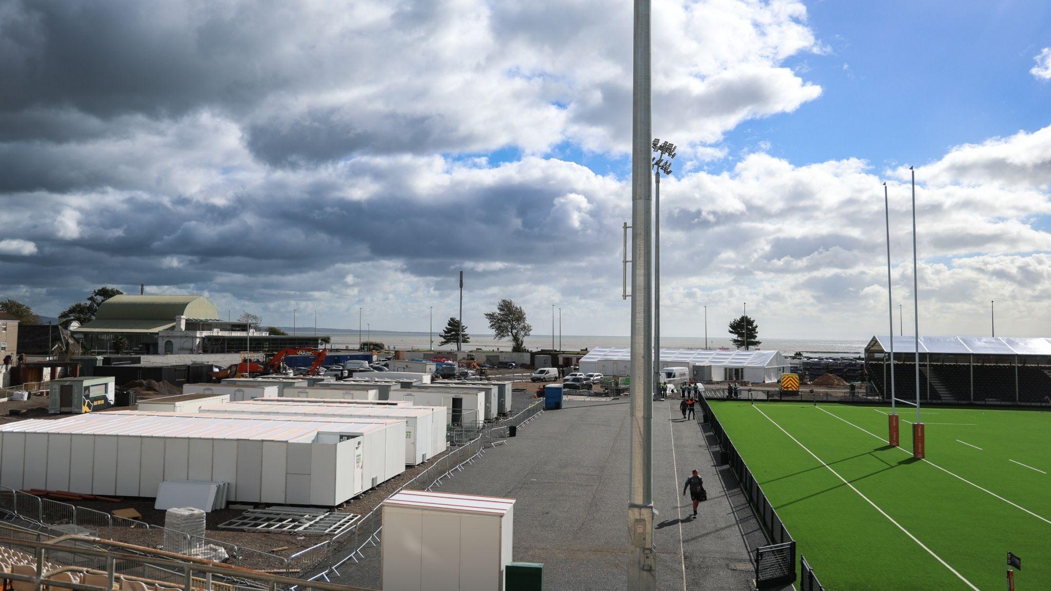 White temporary structures and shipping containers alongside the pitch at St Helen's