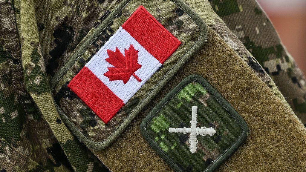 The Canadian flag and Royal Regiment of Canadian Artillery (RCA) Gunner L1 badges are visible on a soldier's sleeve