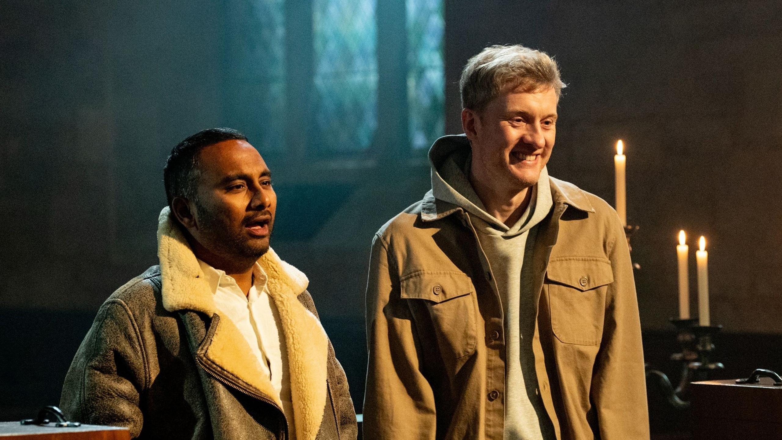 Amol Rajan and James Acaster in the church with candles around them