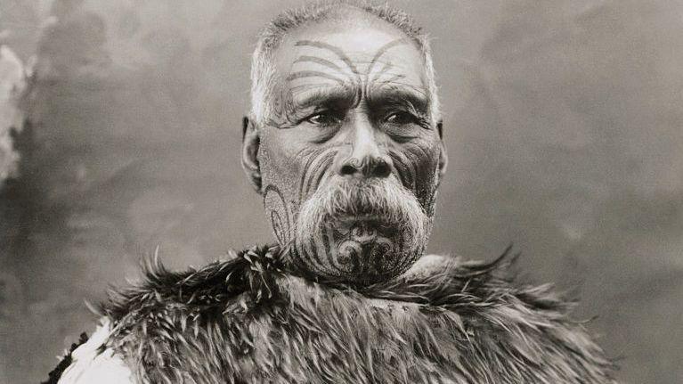 Elderly Maori chief with facial moko and wearing a kahu kiwi (kiwi feather cloak). Circa 1903.