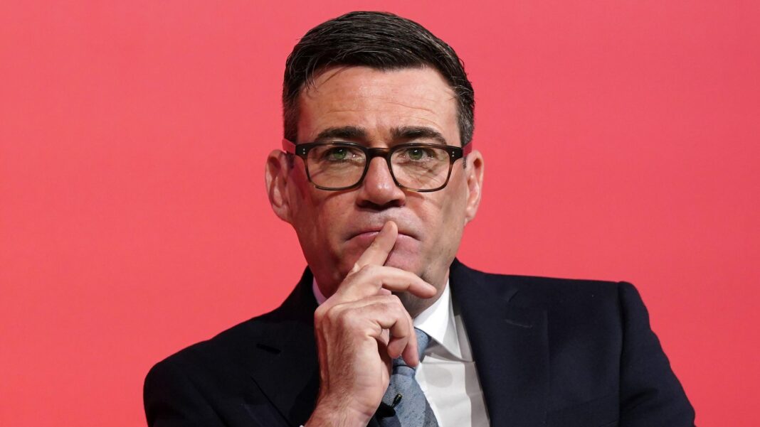 Burnham to hold security talks with German chancellor in Berlin Prime Minister Andy Burnham holds a finger to his lips in front of a pinky-red background at the Labour Party conference on 28 September.