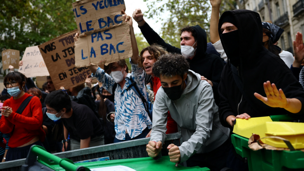 France’s school protests: What lies behind the anger Protesters hold placards behind a barricade to block in Paris, 7 October