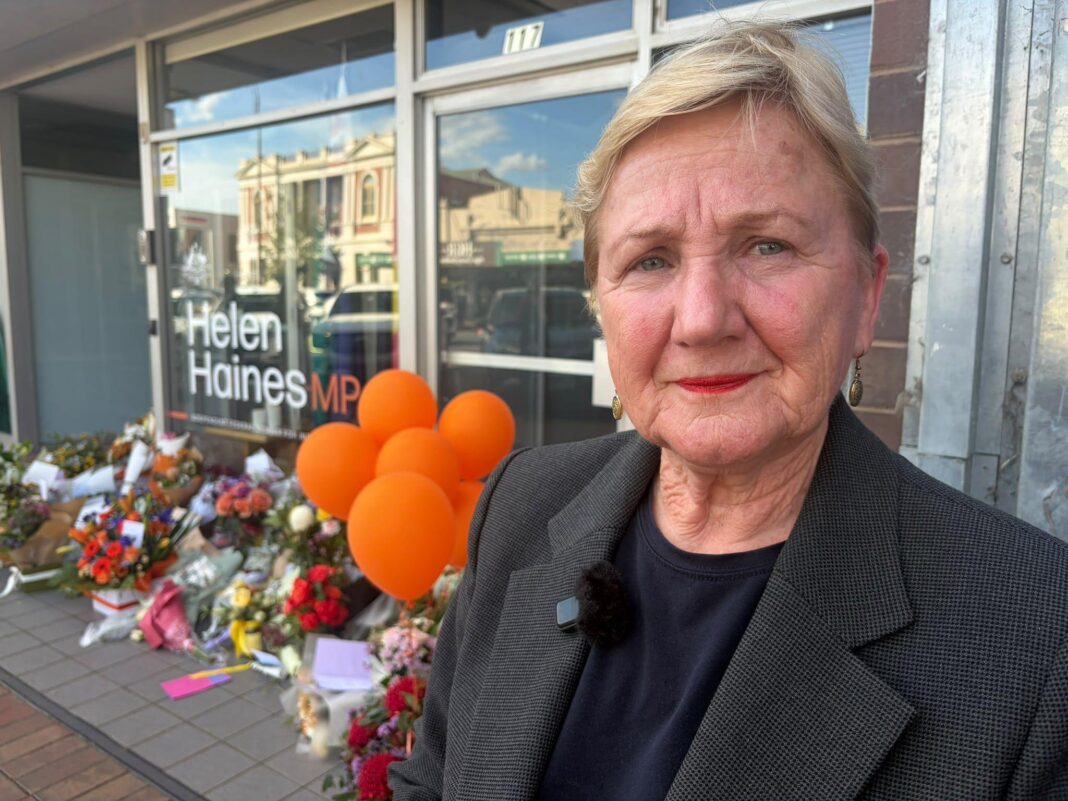 ‘Targeted’ attack on much-loved MP leaves Australian town heartbroken A middle-aged woman with blonde hair stands in front of an glass office window in front of which are flowers and balloons