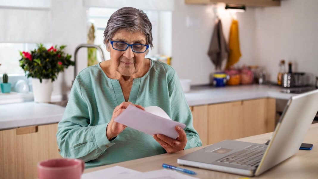 Bereaved families will not face tax bill over pension delays under new rules A woman sitting in front of a laptop opens a letter.