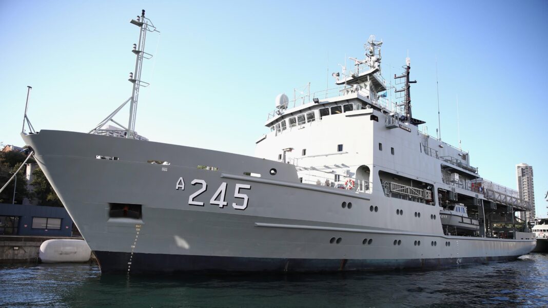 HMAS Leeuwin in the Sydney Harbour in 2013. It is a long grey warship with a blue sky behind it in the harbour.