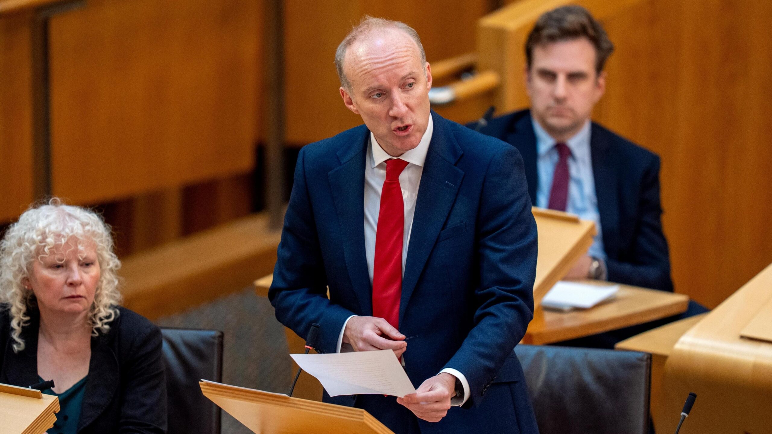 Michael Marra speaking in the Scottish Parliament, holding a piece of paper on his left hand