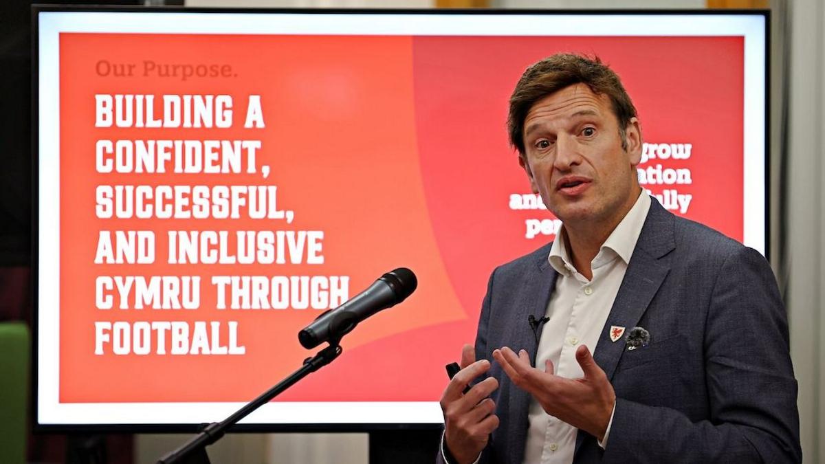 FAW CEO Noel Mooney making a speech in front of a microphone with a slide from a presentation behind him