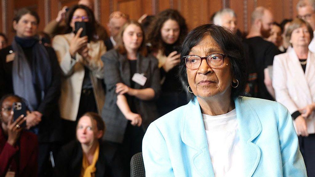 Navi Pillay in a sky blue jacket in front of people congratulating her