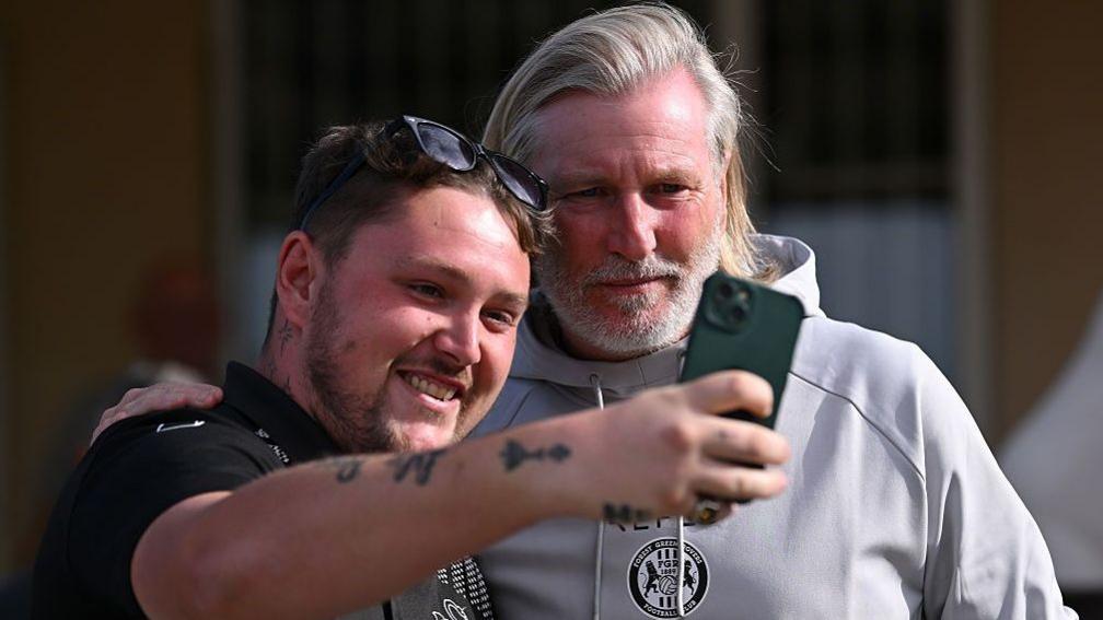 Robbie Savage poses with a Forest Green supporter for a selfie