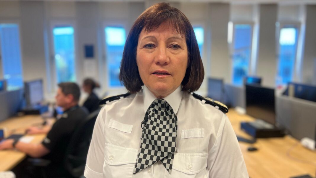 Up to 50 Scottish police officers suspended over alleged crimes against women Jo Farrell looking at the camera. She has dark, shoulder-length hair. She is wearing a white police shirt with large black shoulder panels. She has a black and white checked necktie around her neck. She is standing in front of a blurred background of an office.