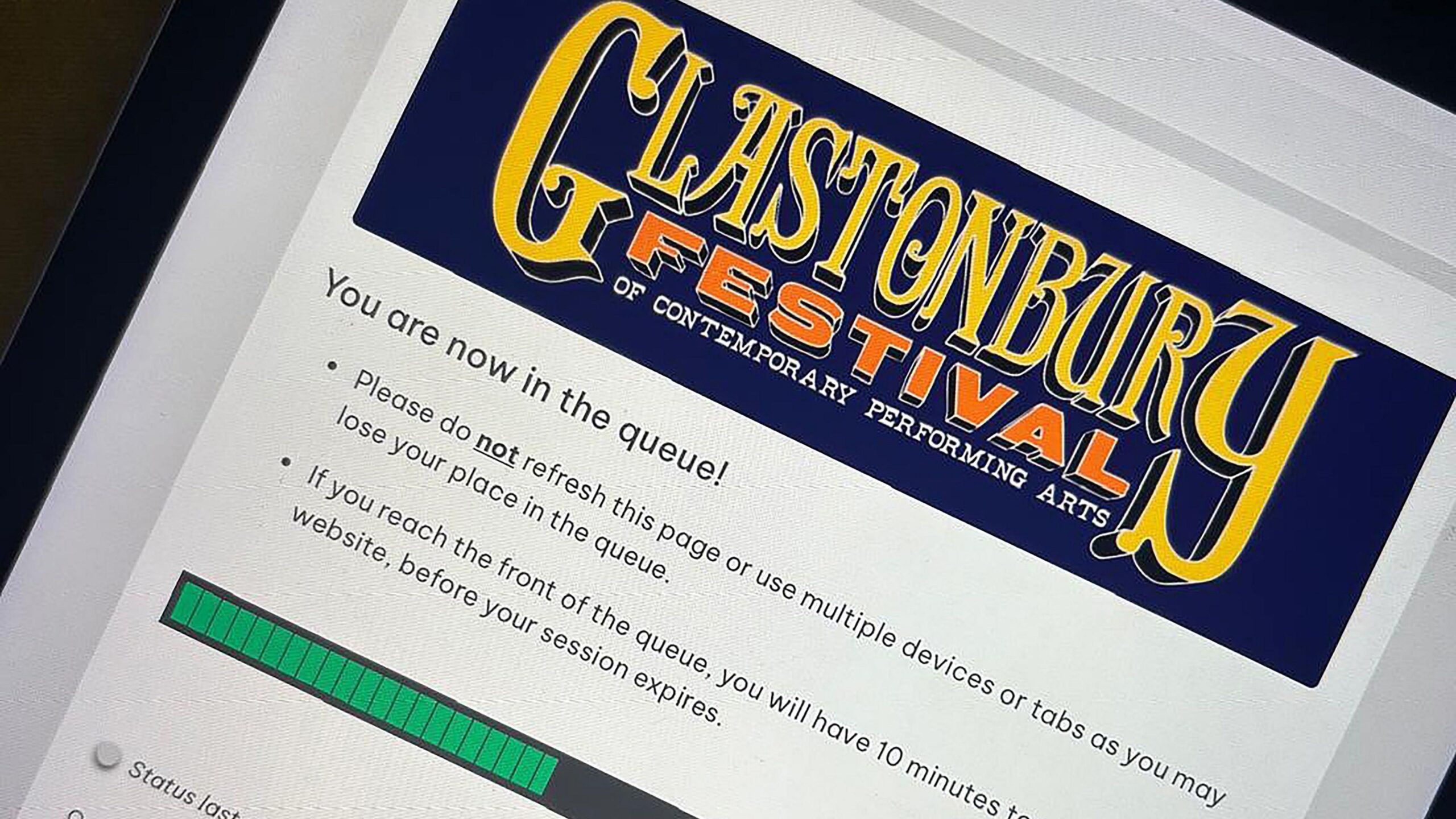A computer screen showing an online queue for Glastonbury Festival tickets. There are instructions telling the user to avoid refreshing the page, using multiple devices and tabs and what to do if they reach the front of the queue. There is a green and black bar showing the progress of the queue at the bottom of the image.