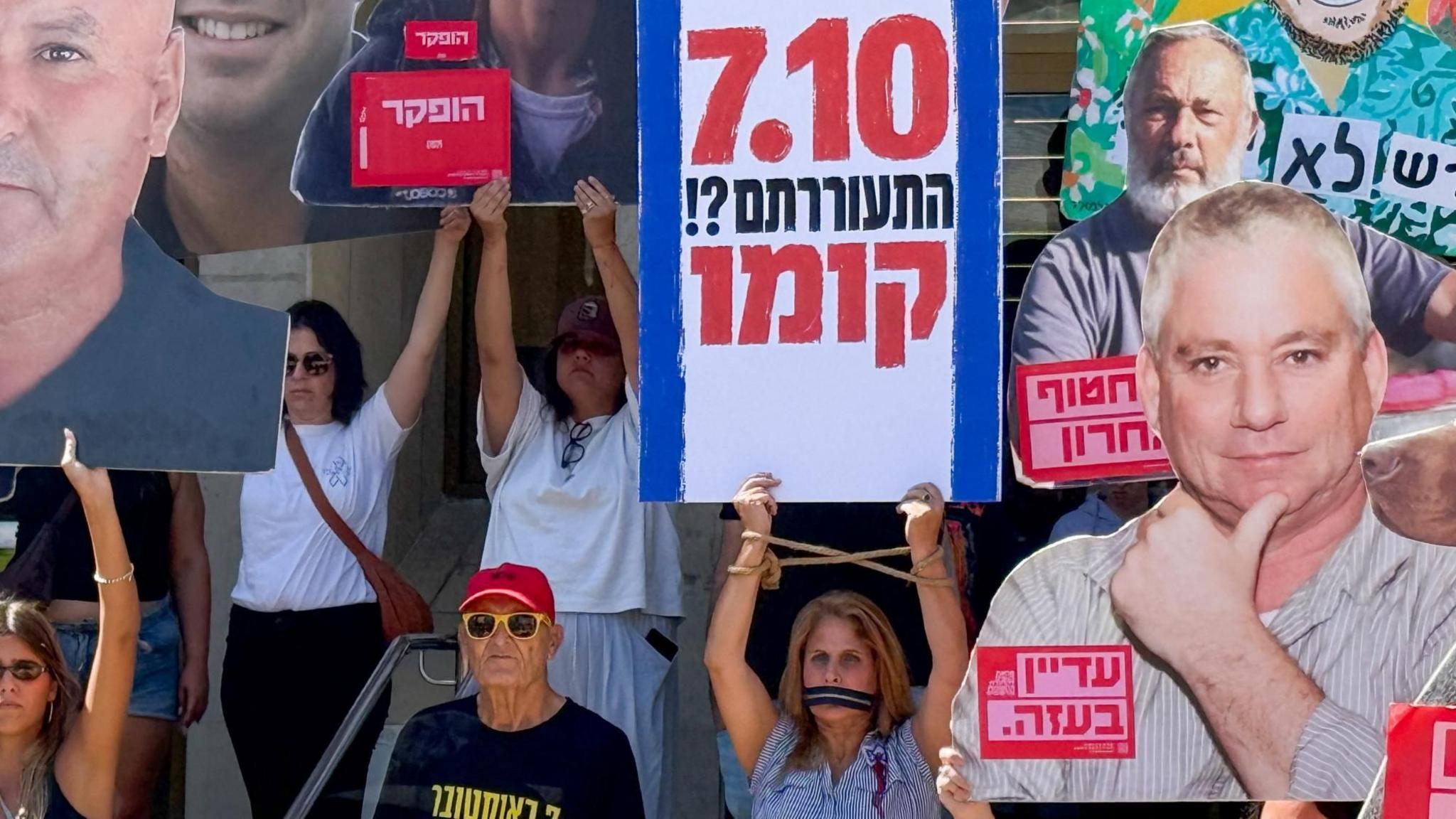 Protesters hold up pictures of dead Israeli hostages and a sign in Hebrew that says "7.10 did you wake up?! Rise up", in Tel Aviv, Israel, on the third anniversary of the Hamas-led 7 October attacks (7 October 2026)