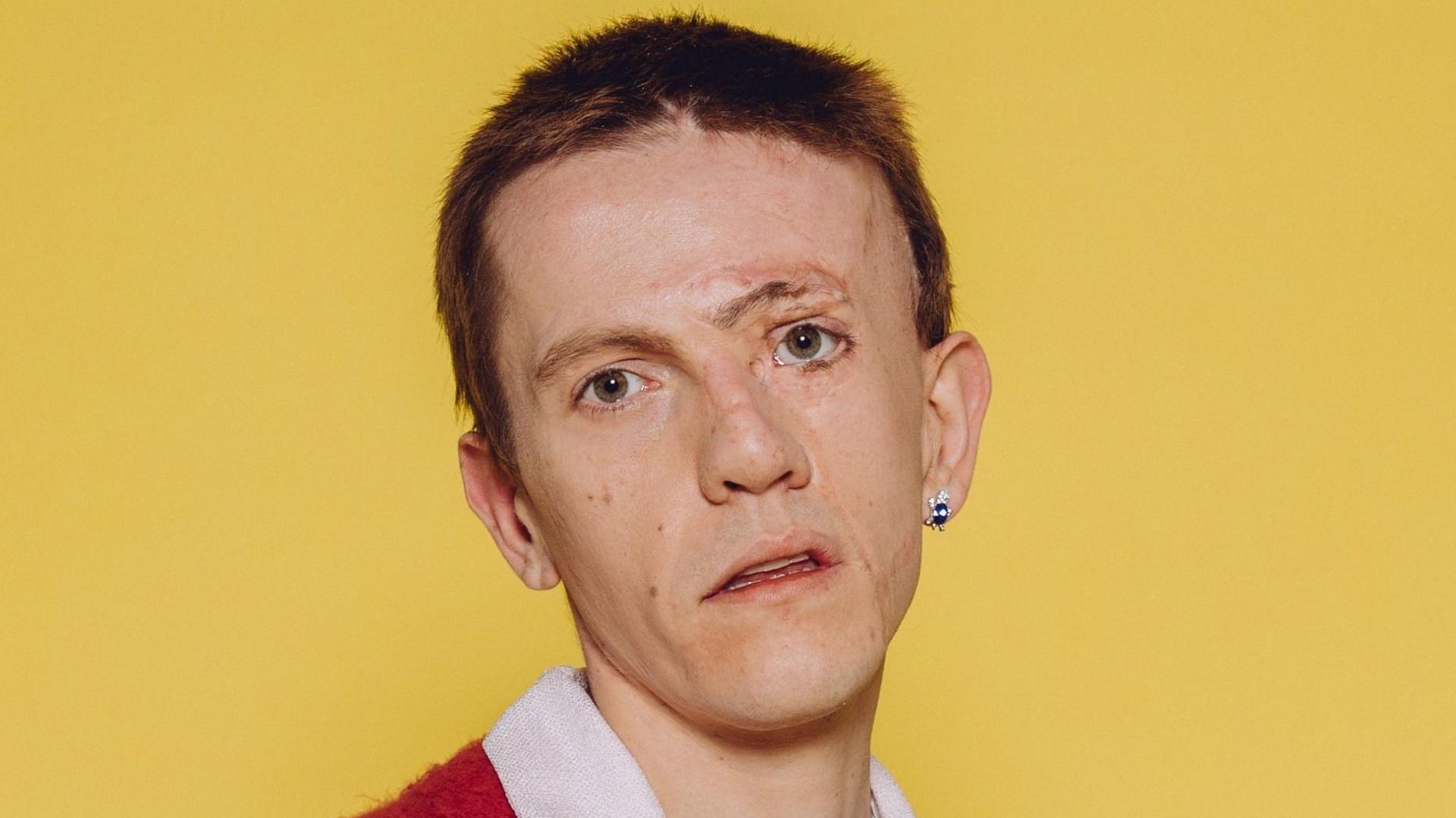 Actor Robert Rhodes looks directly into the camera. He is photographed against a yellow backdrop.