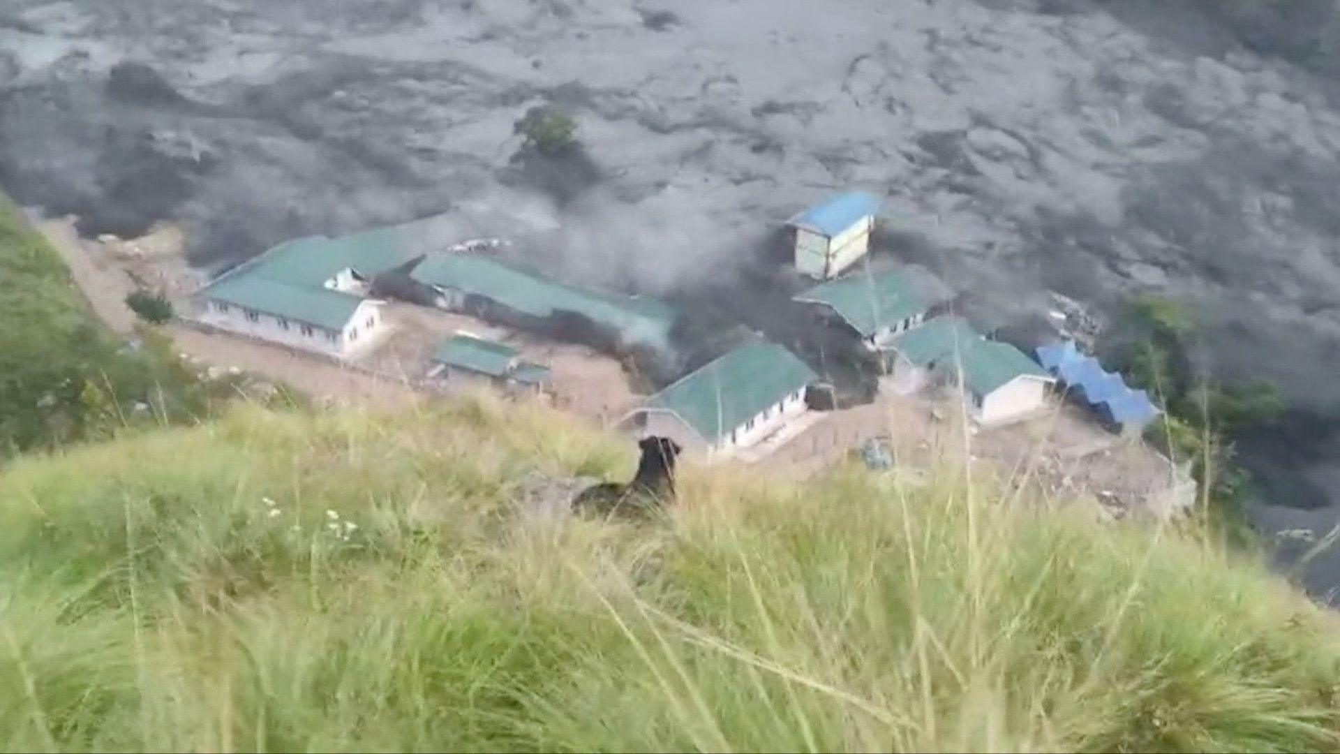 A building complex with green roofs is swamped with black flood water.