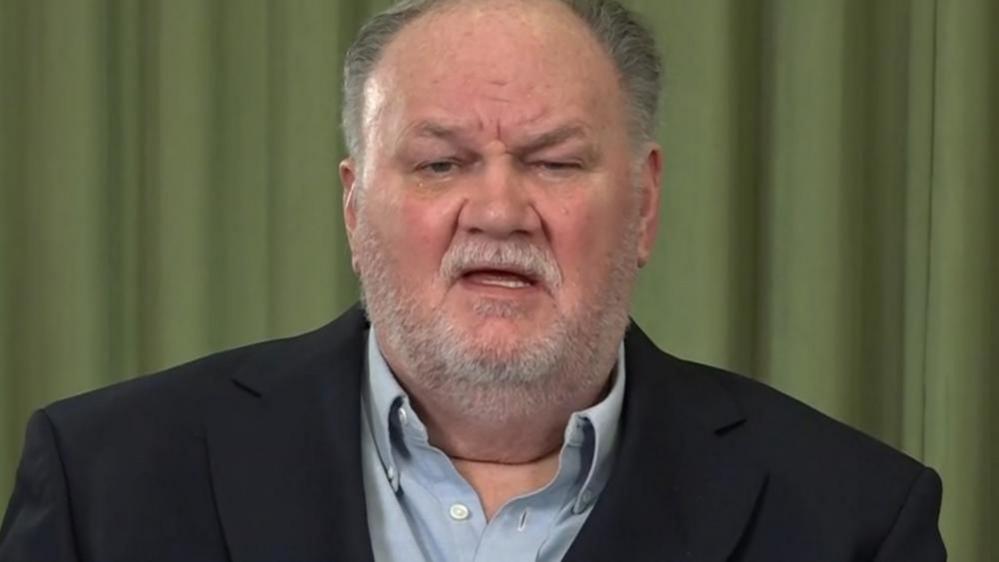 Thomas Markle, an older white man with grey hair and a short white beard. He is wearing a dark blue suit jacket and light blue shirt.