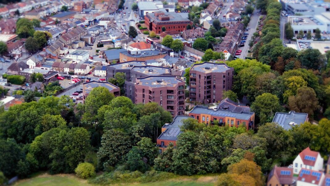 Low rise flats built with purple and pink brinks are nestled in between greenery and high