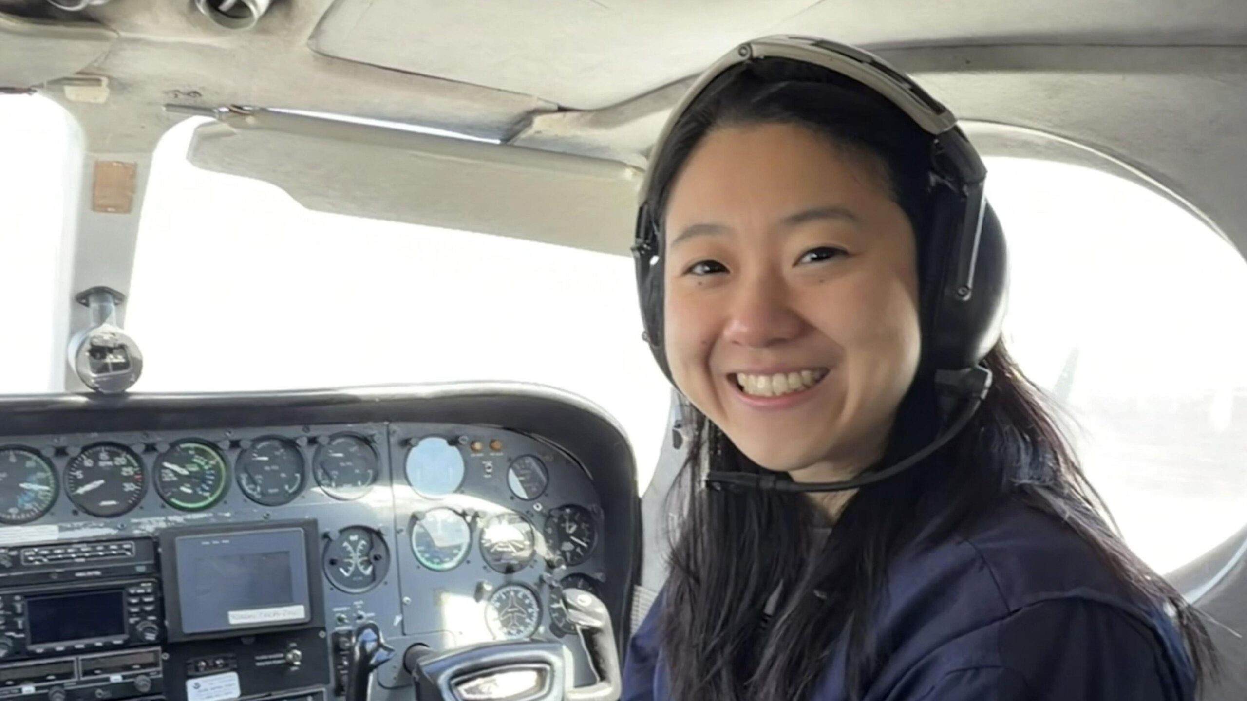 Smiling, Olivia Li is in a light aircraft wearing a headset.