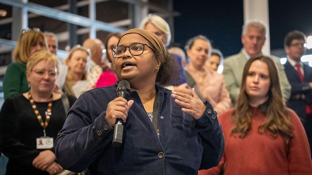 A group of politicians on the Senedd steps, with one holding a microphone and speaking