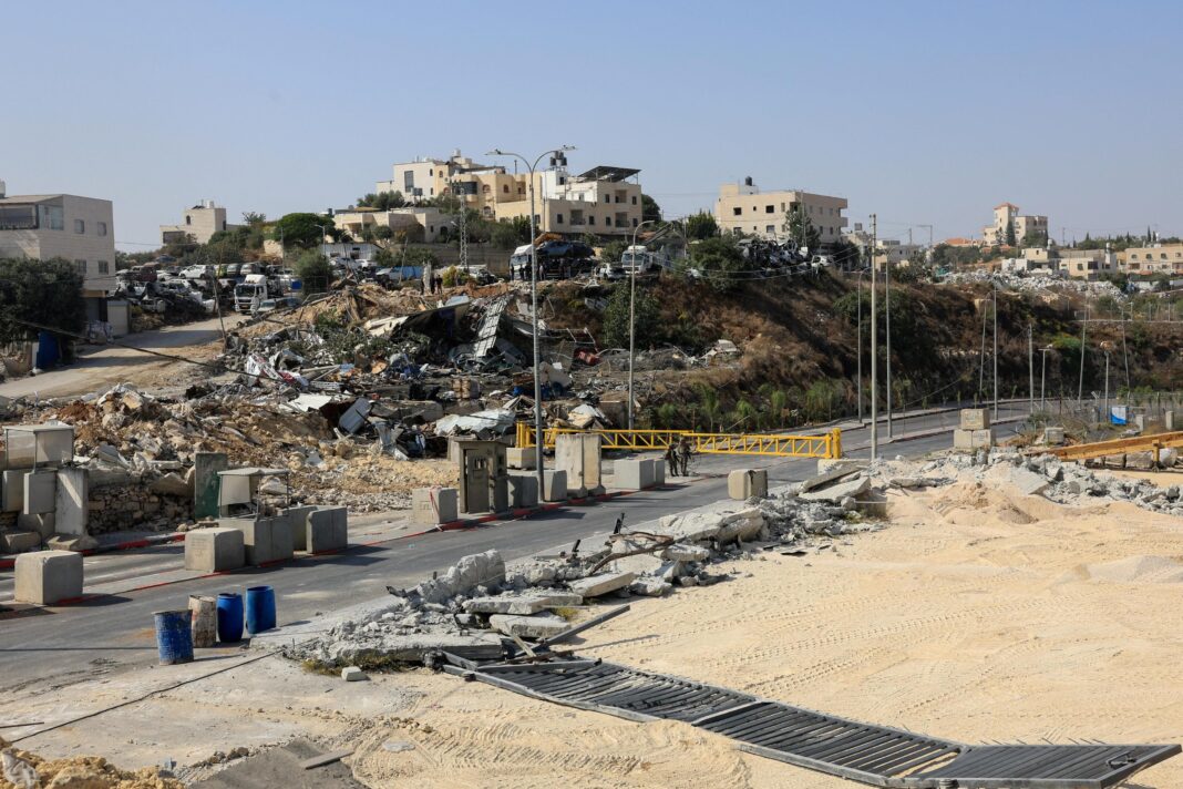 Sandy land around checkpoint. Wreckage in the distance.