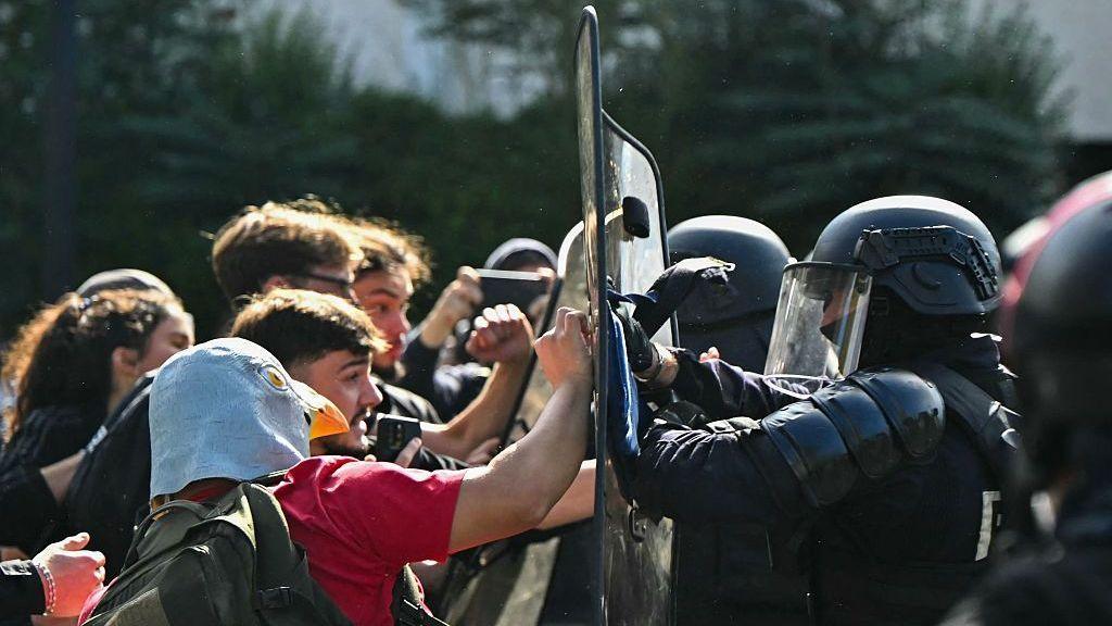 Anti-riot police officers face protesting students carrying out blockading action outside the secondary school Le Corbusier, in Aubervilliers, northern Paris on October 1, 2026. Since late September, students have staged protests outside schools over grievances ranging from timetables, class sizes and a shortage of teachers to overheated classrooms during this year's heatwaves. The protests started in the Ile-de-France region around Paris but have now spread to other cities nationwide