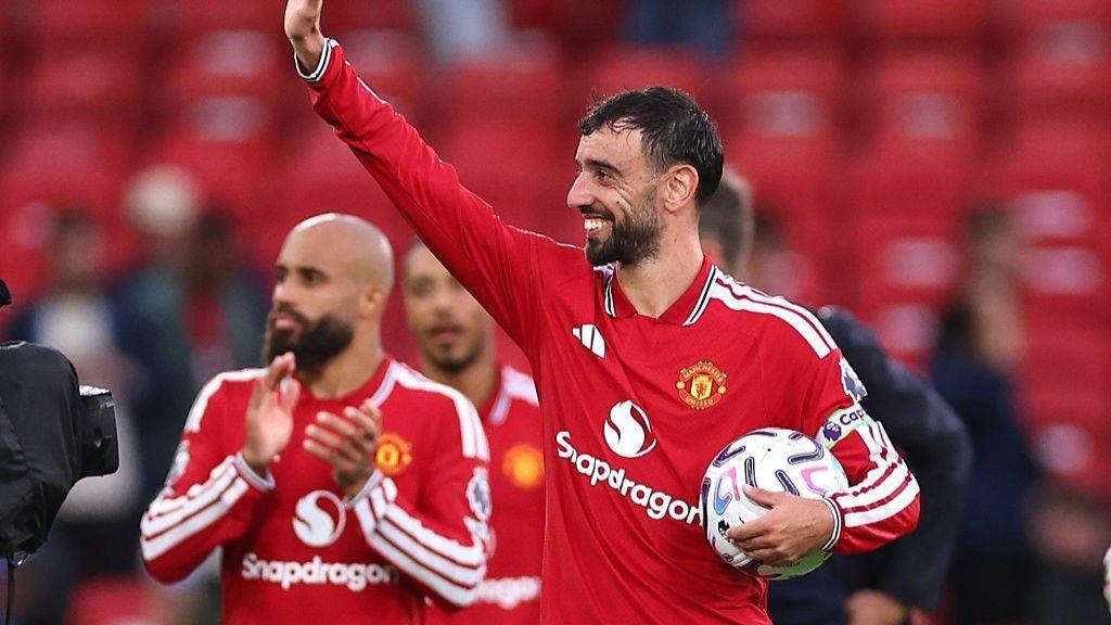 Bruno Fernandes holding the match ball and waving to fans after his hat-trick against Ipswich