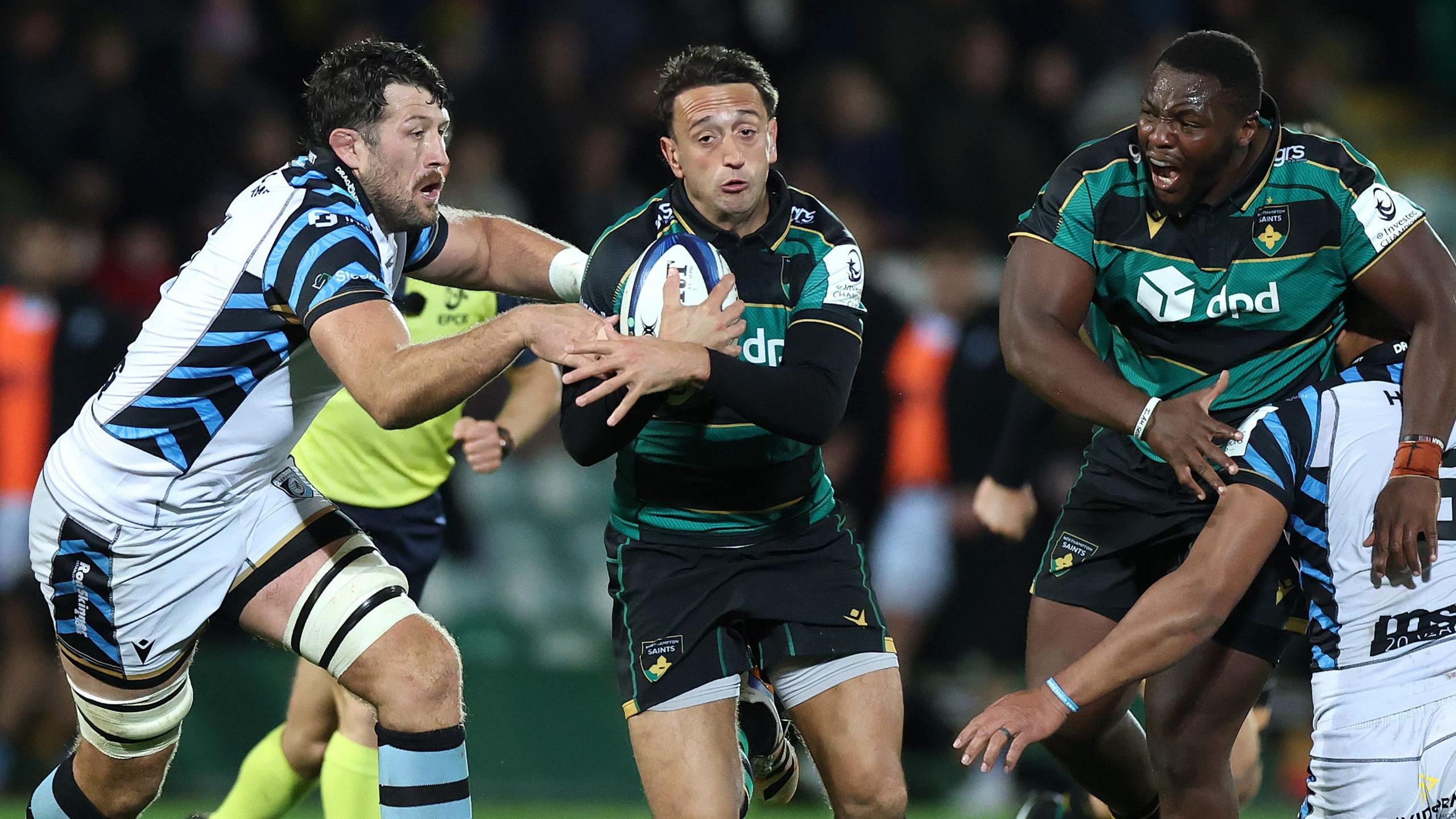 Northampton scrum-half Alex Mitchell with rugby ball in hand evades Cardiff defenders