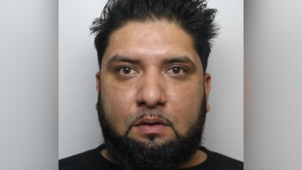 A custody photo of a man with short spiked hair and a trimmed beard, looking directly at the camera against a plain background.