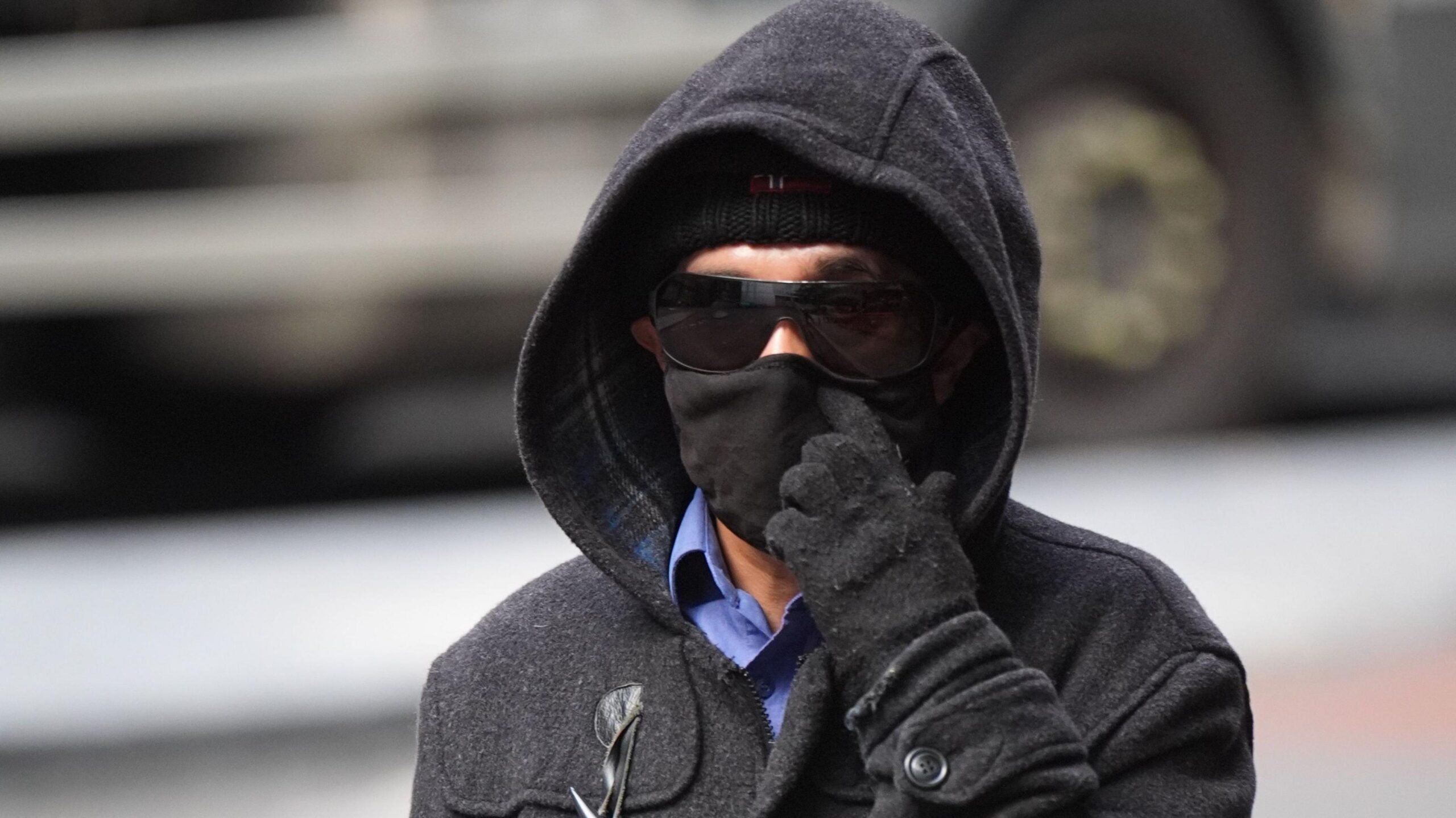 Kashim Chowdhury wears dark sunglasses, a hat, hoody and gloves as he arrives at court. His face is largely obscured.