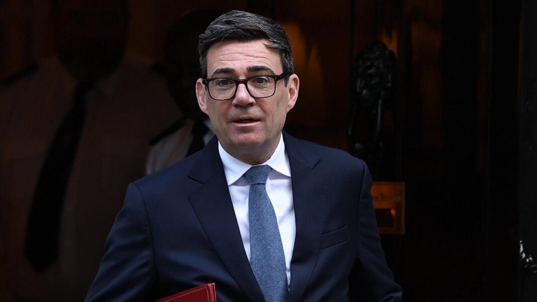 Andy Burnham leaving Downing Street. He is wearing a dark blue suit, blue tie and glasses. He is carrying a red folder.