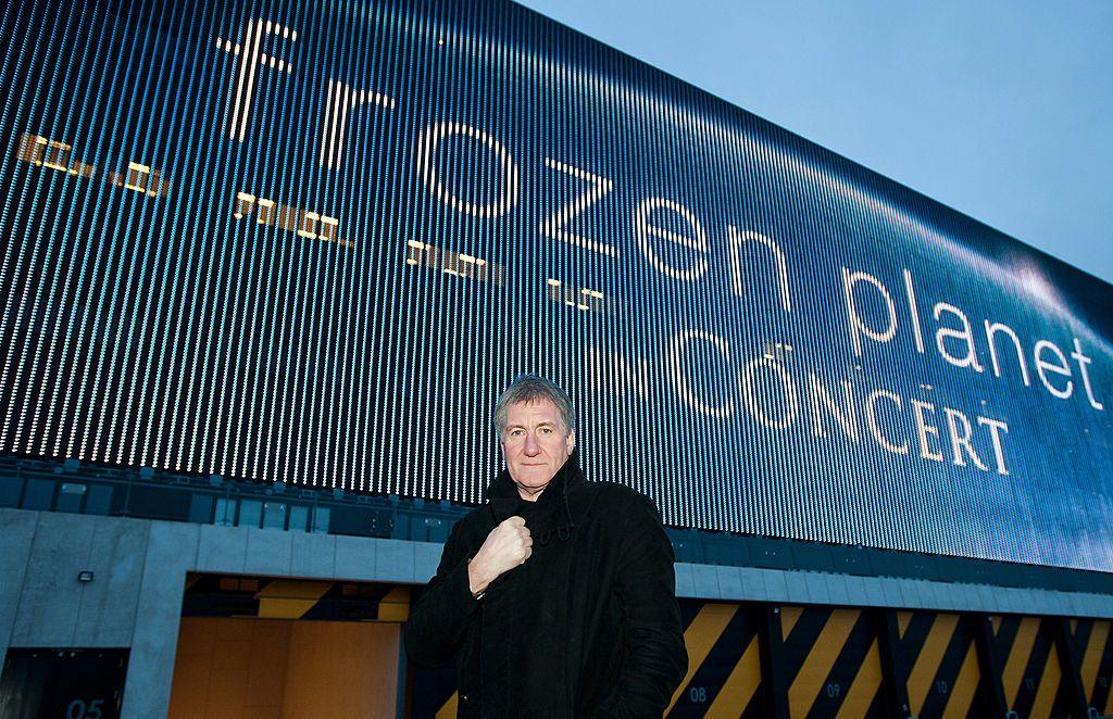 George Fenton stands next to a billboard promoting his orchestral show The Frozen Planet Live