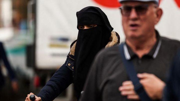 A woman in a niqab pushing a pram