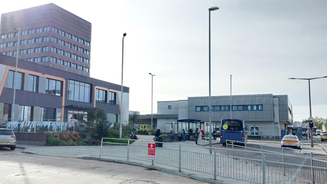 NHS staff get ‘landmark’ payout over gas exposure Exterior views of several hospital buildings. To the left is a taller, high rise type building. In the foreground is a road and a pedestrian barrier. Cars and a bus are visible alongside people waiting at a bus stop.