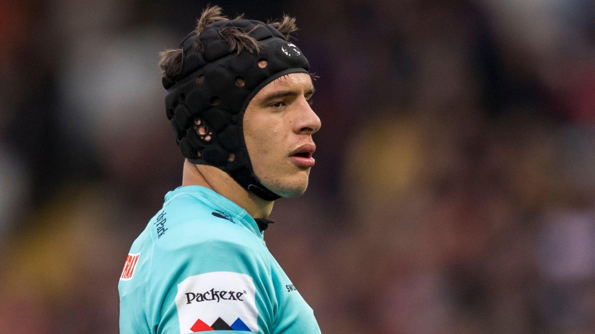 Dafydd Jenkins looks on in a balck scrum cap and blue-green jersey