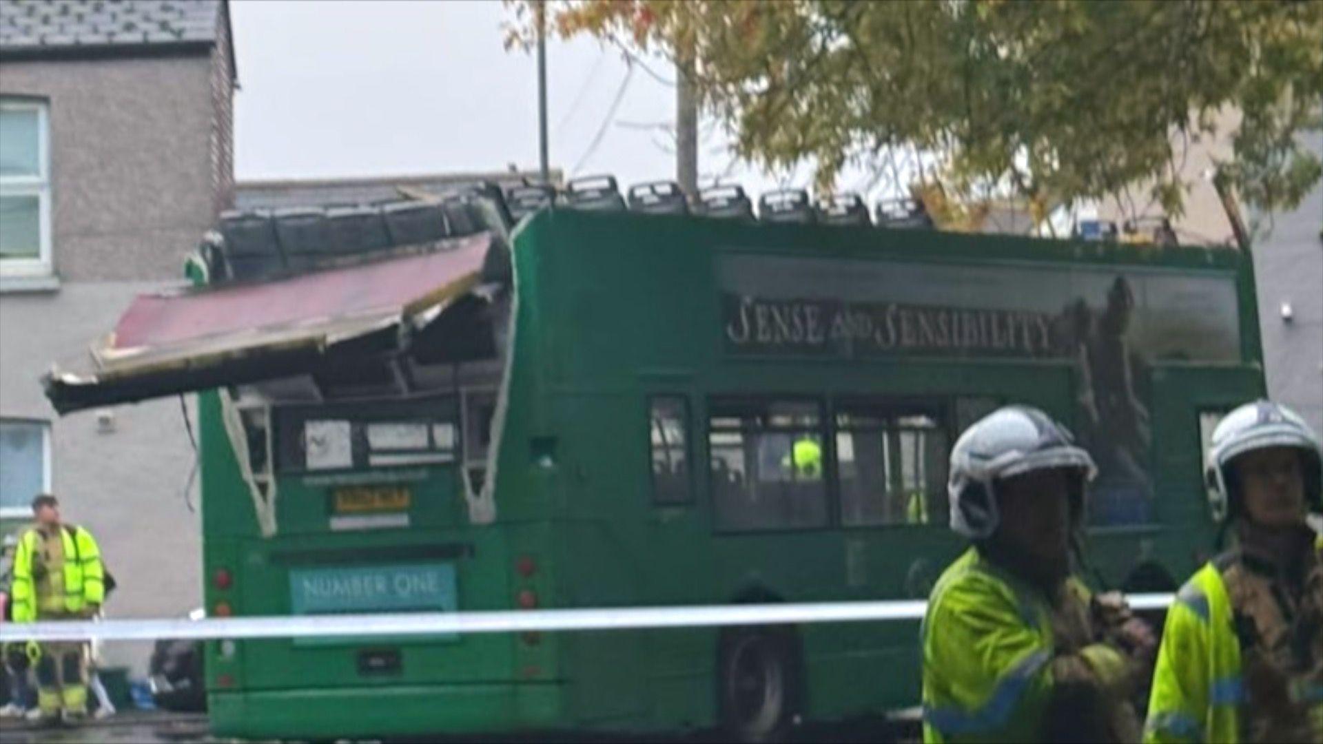 Double decker green bus pictured in a street. The roof of the bus is completely off, with some of it hanging off the back.