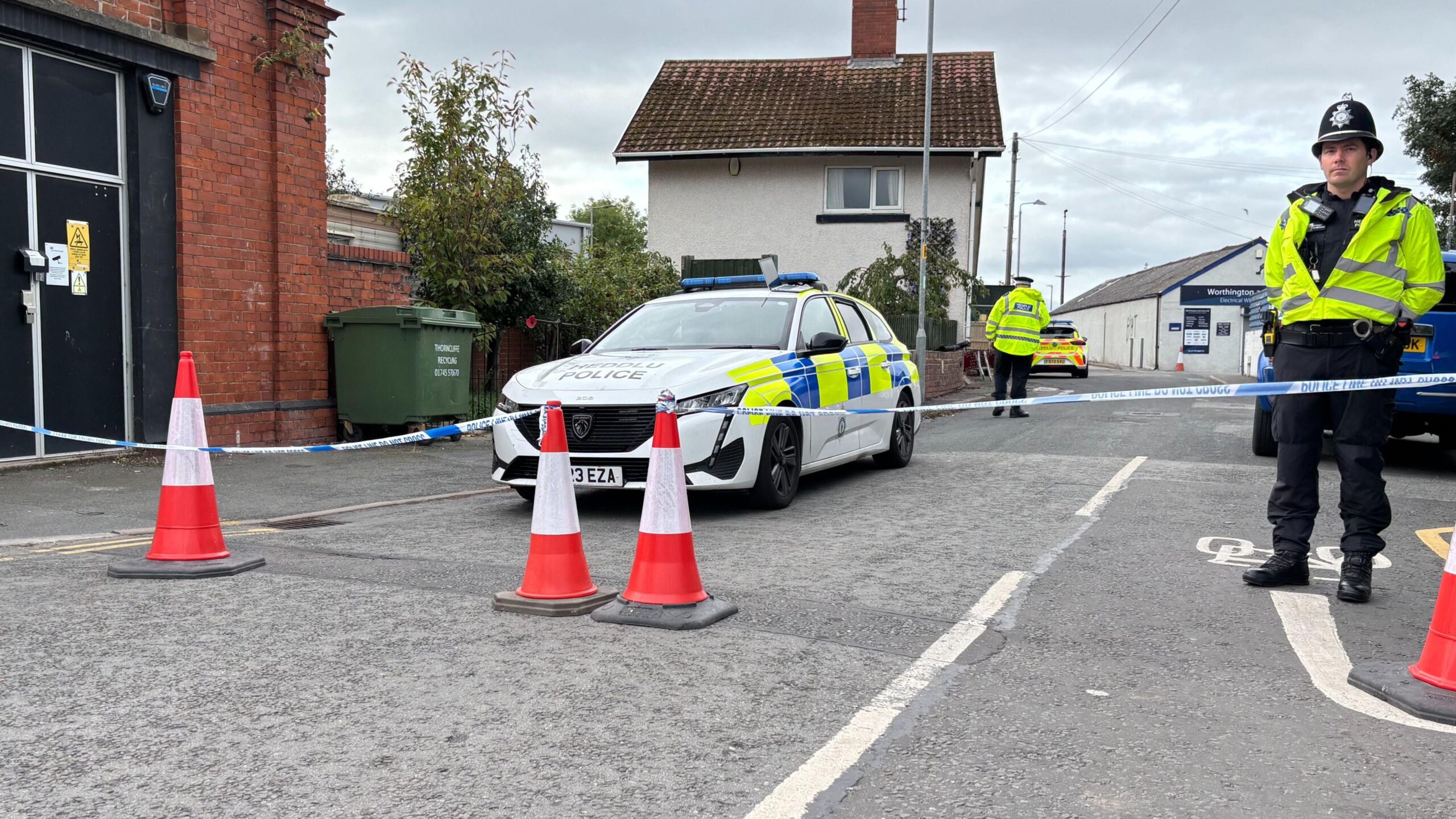 Police car and police officers behind a cordon and orange cones on a street