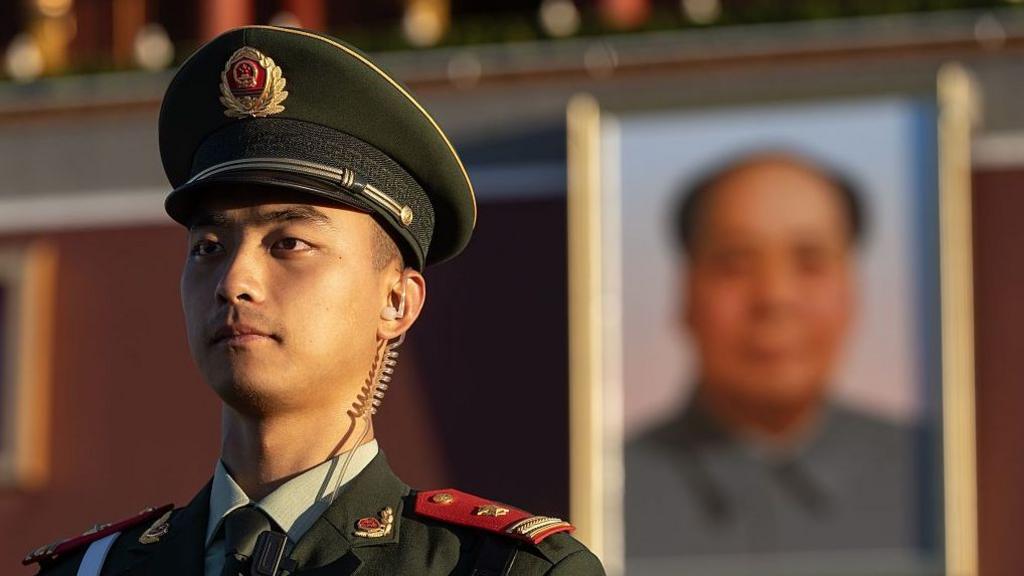 A soldier stands guard in Tiananmen Square after the flag raising ceremony as China marks the 77th anniversary of the founding of the Peoples Republic, in Beijing.