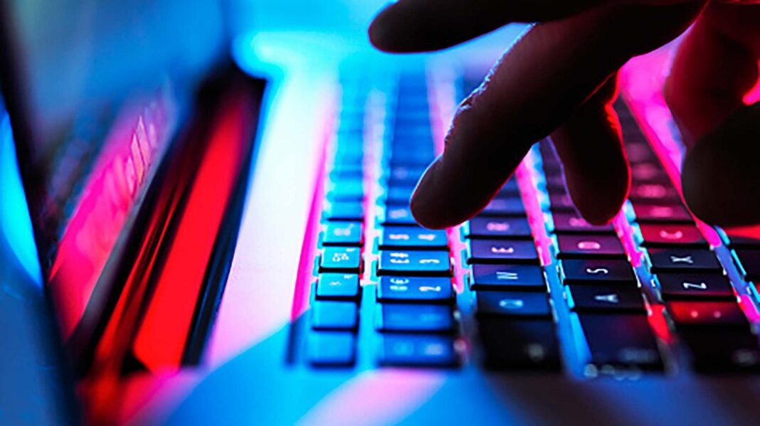 A stock picture showing a laptop with some hands tapping keys with neon lighting