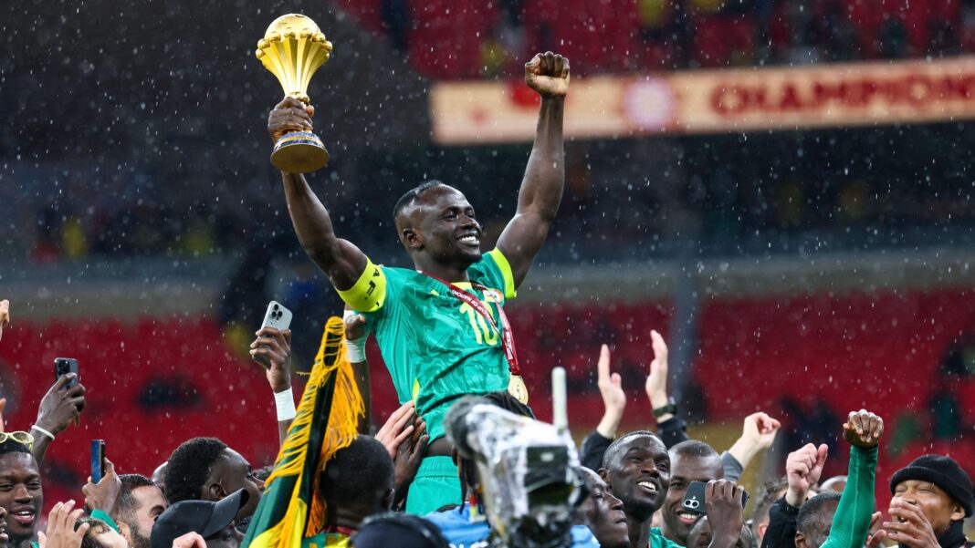 Afcon final to play out in court – when will Morocco or Senegal be crowned champions? Sadio Mane, wearing green Senegal kit and with a golden medal around his neck on a red ribbon, is raised on the shoulders of his team-mates after the final of the 2025 Afcon. As drops of rain fall, Mane raises both arms in the air, clutching the Afcon trophy in his right hand. The heads of the group gathered around him can be seen, with a mix of hands also raised, some clapping, others filming on phones, while a TV camera with a rainproof cover is also visible in the throng
