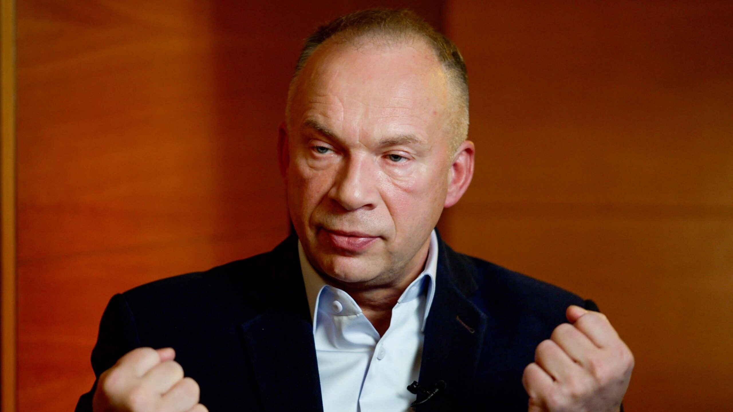 Oleksandr Syrskyi bunches his fists and sits in a dark blue jacket and light blue shirt