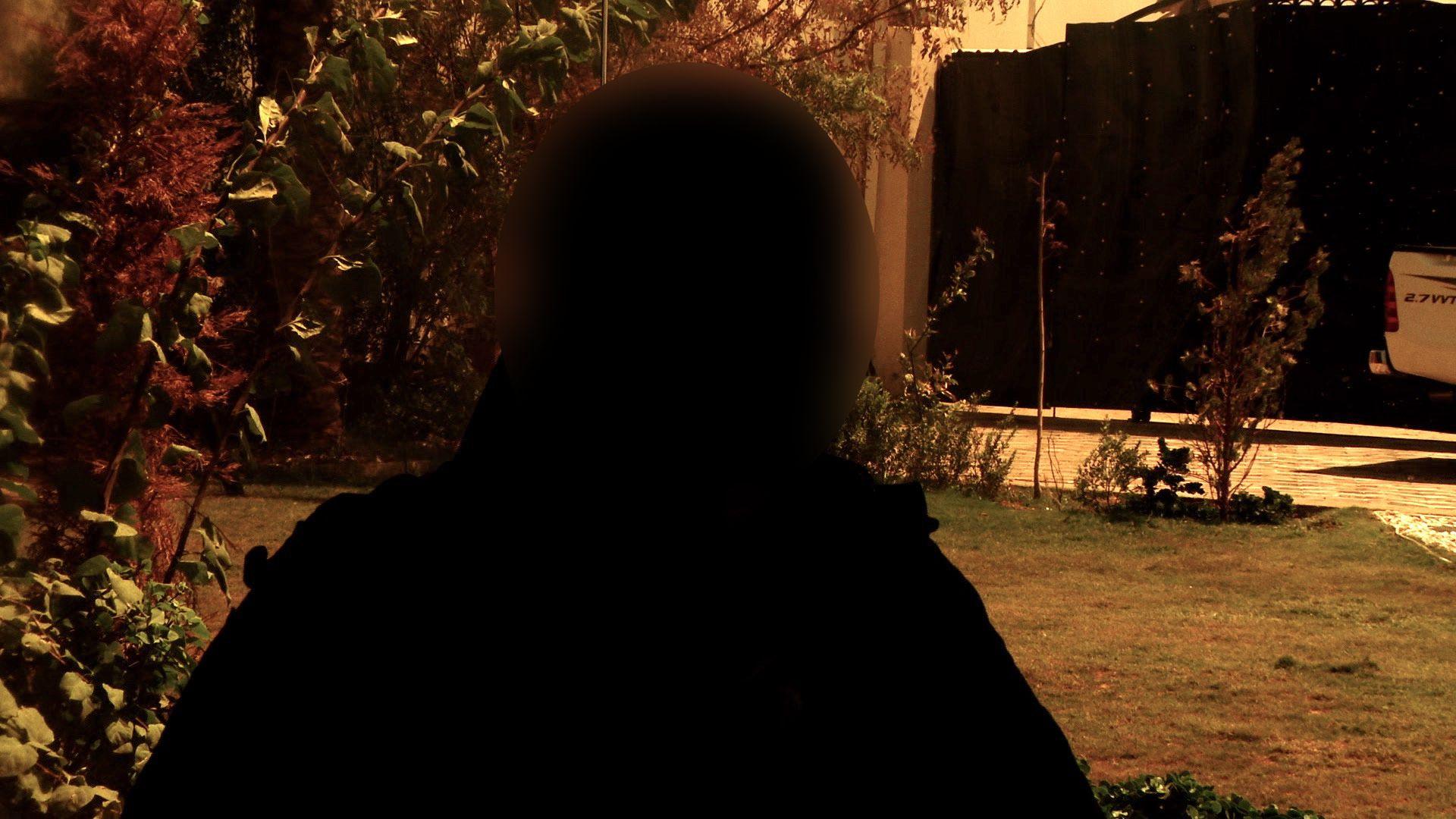 Silhouette of Amal’s veiled head and shoulders, with the head slightly blurred and a garden in the background