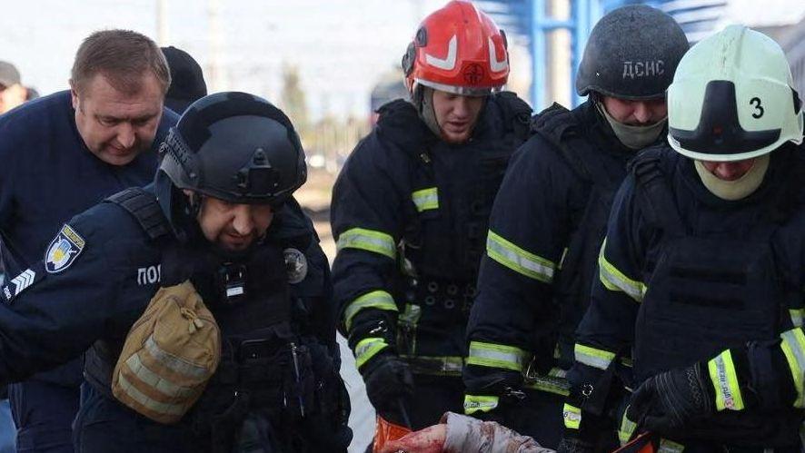 A group of men carry an injured person, who is out of shot, from a railway station after a strike in Dnipro.