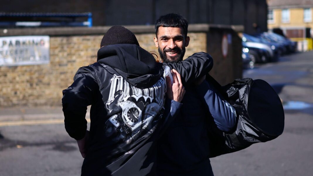 A released prisoner (R) is greeted by a friend as he leaves HMP Wandsworth prison in south London, Britain, 13 October 2026. Two men are pictured greeting each other. One is smiling, the other has his back to the camera.