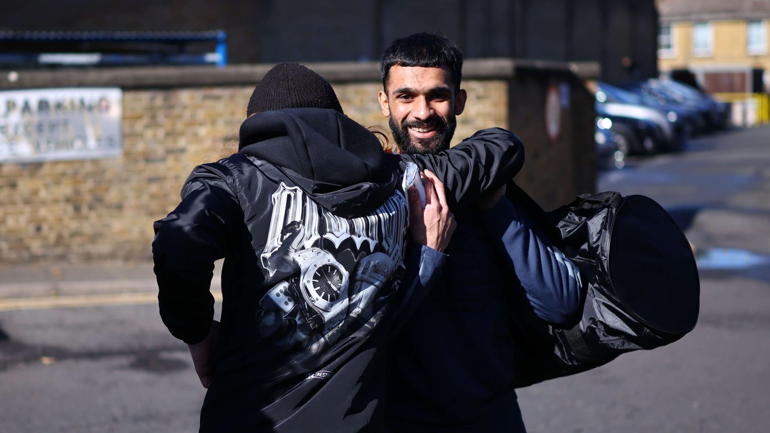 A released prisoner (R) is greeted by a friend as he leaves HMP Wandsworth prison in south London, Britain, 13 October 2026. Two men are pictured greeting each other. One is smiling, the other has his back to the camera.