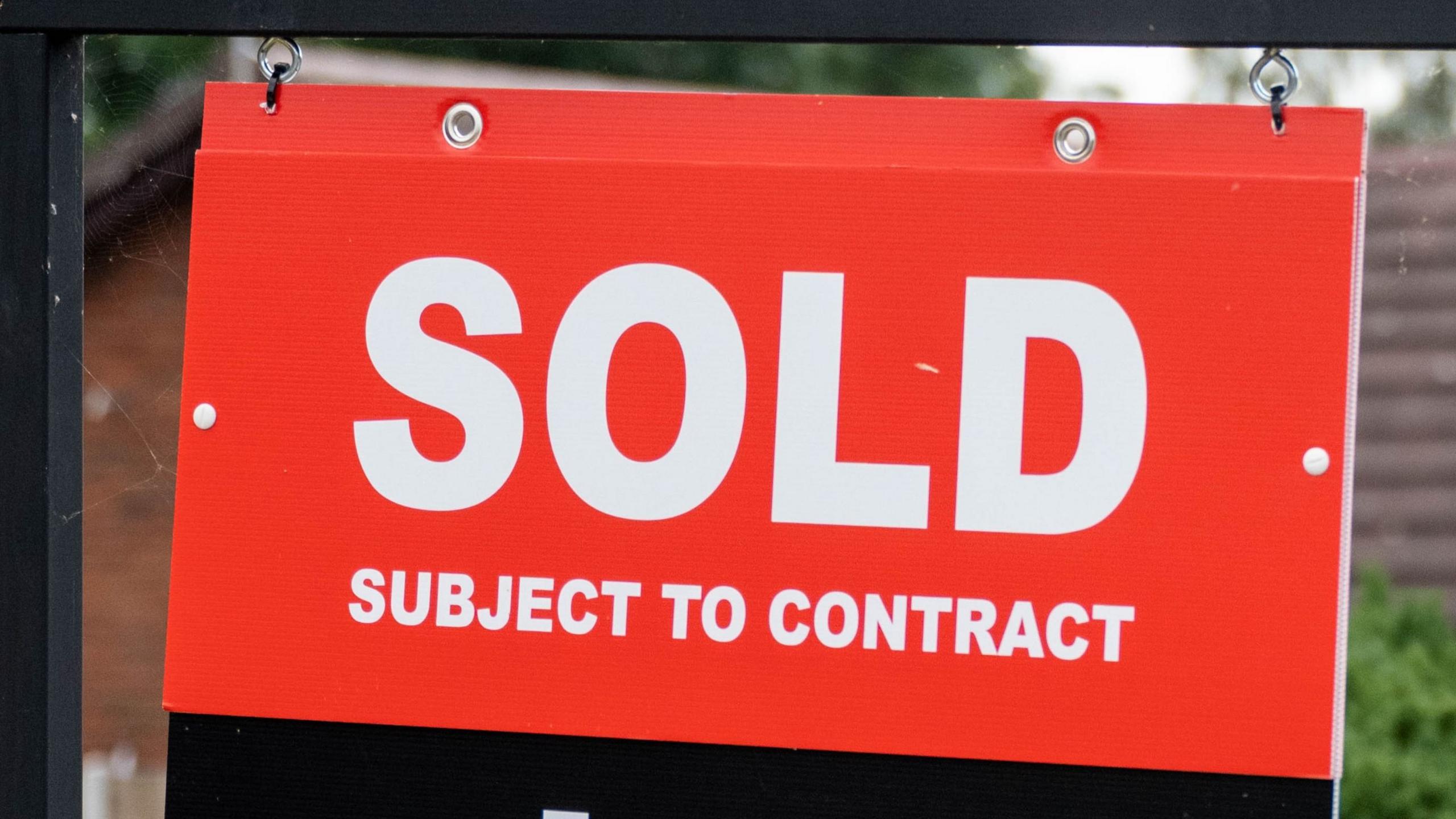 Red, black and white sold sign outside a house