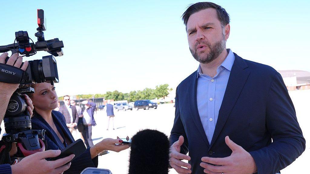JD Vance talks with reporters on a tarmac