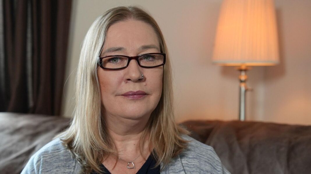 My son has disappeared off the face of the earth fighting for Russia Valerie Stobbart has shoulder-length blonde hair and narrow, black-rimmed glasses and has a neutral expression. She is wearing a grey cardigan and black top, with a silver necklace with a charm in the shape of an outline of a heart on it. She is sitting on a dark sofa and behind her are brown curtains and a cream lamp-shaded standard lamp against a cream wall. The lamp is switched on, emitting a warm peach glow.