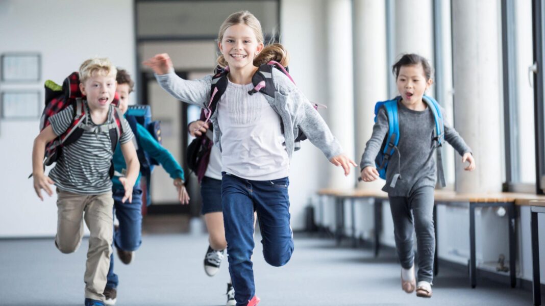 Two-week half terms: The school holiday no one can agree on School children running through a hall way with school bags on.