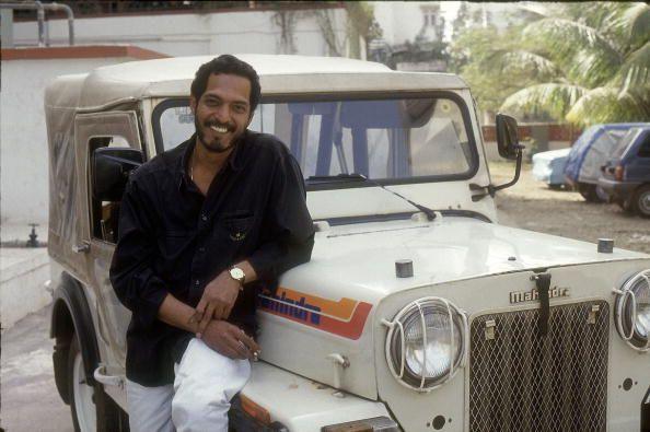 An old photo of Nana Patekar standing next to a jeep in Mumbai in a black shirt and white trousers