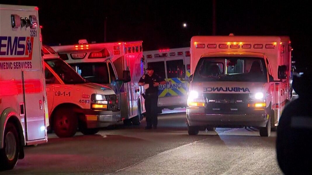 Several dead or injured in major fire at Canada military base Ambulances line Wainwright health centre after the deadly blast at Canadian Forces Base Wainwright. Five emergency medical vehicles can be seen with their lights on, glowing red in the darkness. A man in uniform can be seen in the background.