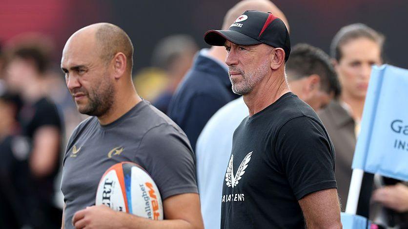 Saracens head coach, Joe Shaw (left), and head of culture and technical director, Brendan Venter, look on from the sidelines before the match with Sale